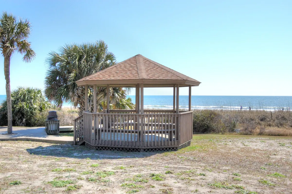This image captures a picturesque gazebo surrounded by palm trees, set against a stunning ocean view. The peaceful setting invites gatherings, casual socializing, and relaxation while watching the sunset or sunrise. The open-air vibe suggests a connection to lively beach events and the vibrant nightlife atmosphere described in the section.